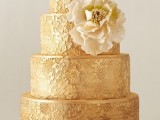 a gold patterned wedding cake with a neutral sugar bloom is a great idea for a very exquisite wedding