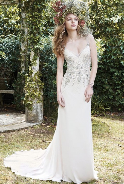 a beautiful embellished wedding dress with a V-neckline, illusion straps,a train and an oversized floral crown for a unique bridal look