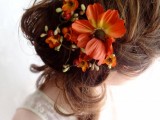 a messy half updo with a braid and curls down with bold faux fall blooms to make the look more eye-catchy and fall-inspired