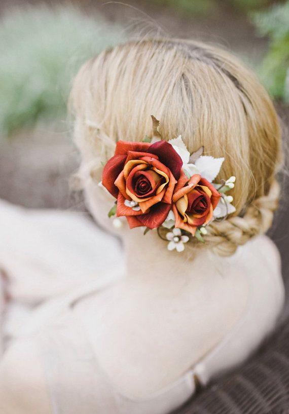 A lovely wedding updo with a braid and a bold floral accent with burgundy roses and some leaves for a delicate fall bride's or bridesmaid's look