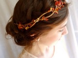 a messy low updo with a large braid halo and a twig headband with faux blooms and leaves for a more fall-like look