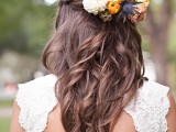 a pretty half updo with a braided halo and waves down plus fresh orange, white blooms, a seed pod and a thistle piece is a lovely idea for the fall