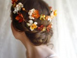 a delicate low updo with a twisted part and a bright fall floral crown is an amazing solution