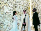 two white floral walls with built-in lights in between to accent the backdrop and the couple