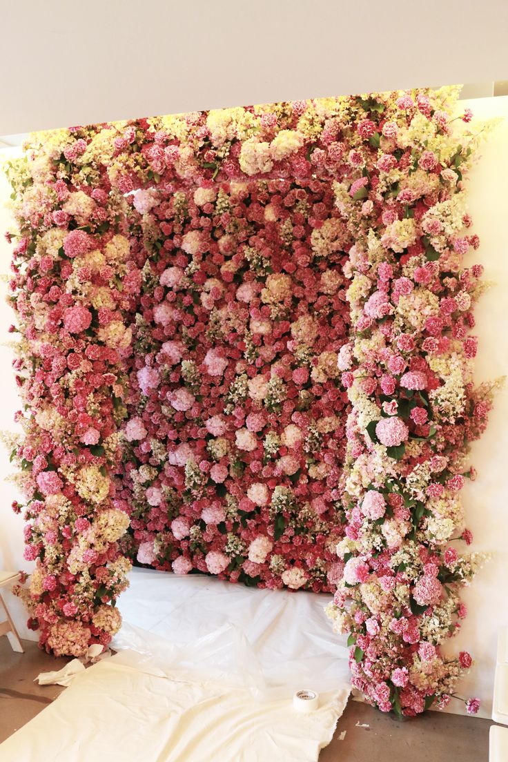 A lush red, white and pink floral wall backdrop and a matching arch to dive into the florals completely