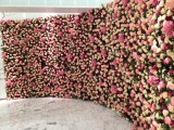 a long curved floral wall with white and pink roses is a gorgeous wedding and photo booth backdrop