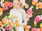 a bright floral wall with orange, pink, peachy and blush blooms and a moss background