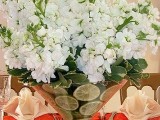 a white floral centerpiece with lemon slices in a cone-shaped vase is a fresh and bright idea for a spring wedding