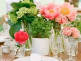 a bright pink and red floral centerpiece paired with a green hydrangea one for a bold spring wedding