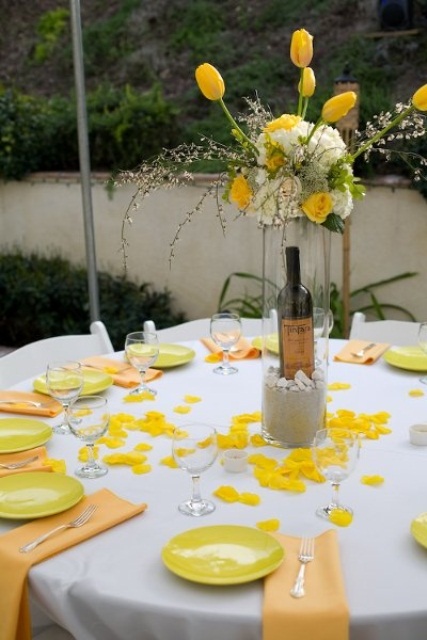 a bright spring wedding centerpiece composed of white and yellow blooms and some blooming branches