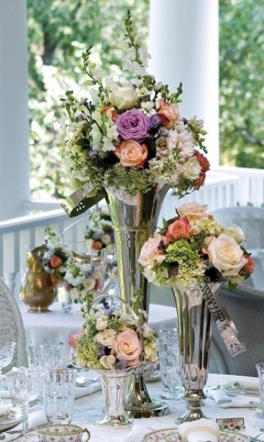 whimsy floral wedding centerpieces of silver vases with peachy, blush and purple blooms and greenery