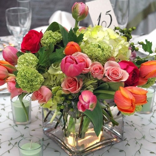 a pink, red, orange and green floral and greenery wedding centerpiece is great to bring much color to the table