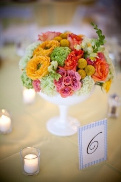 a bold spring wedding centerpiece in marigold, pink, red and yellow plus a white bowl for spring