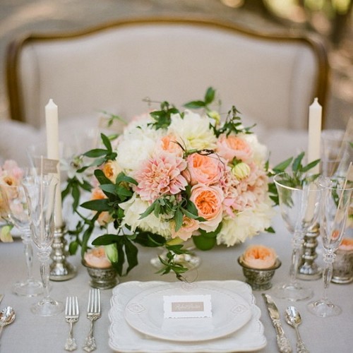 a white, peachy and light pink floral wedding centerpiece with greenery and candles is an elegant idea