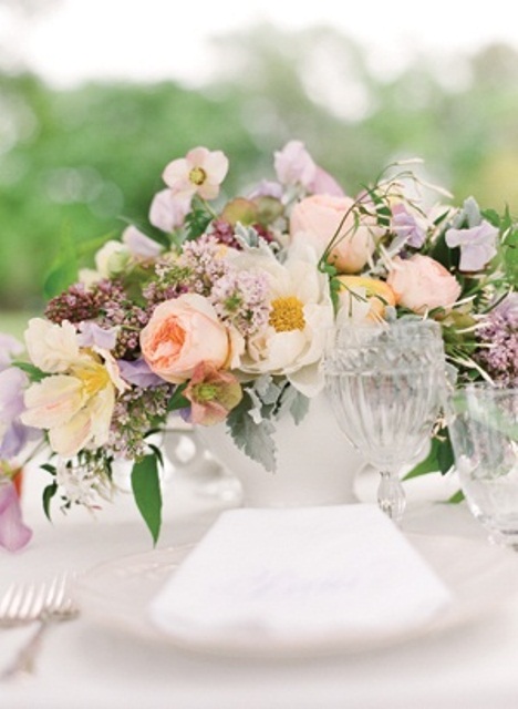 a pastel wedding centerpiece in peachy, lilac, light pink and some greenery for a spring wedding