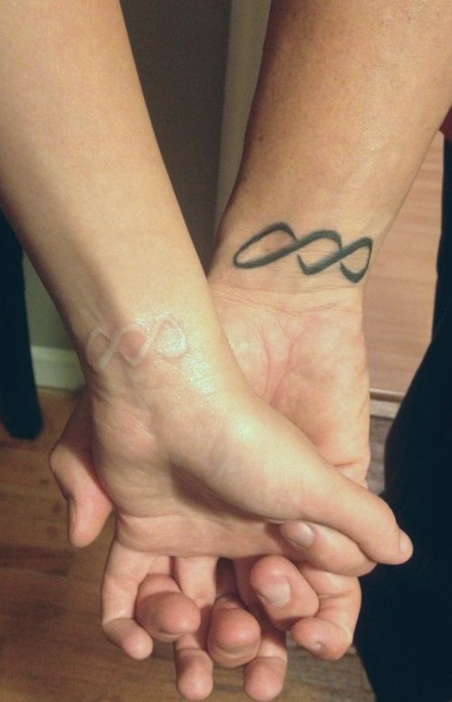 double white and black infinity signs on the wrists are small yet stylish tattoos with chic