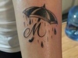 your partner’s monogram with an umbrella and rain around is a creative forearm tattoo to make