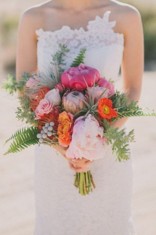 a bright wedding bouquet of pink peonies, pincushion proteas, red anemones, greenery and berries is a bright idea for summer