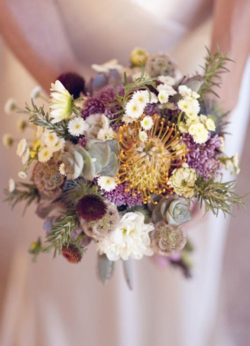 a whimsical wedding bouquet of chamomiles, lilac blooms, seed pods, succulents and pincushion proteas