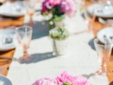 a lively spring wedding tablescape with a neutral runner, mercury glass vases with succulents and pink peonies plus amber glasses