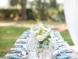 a pastel spring wedding table with a burlap runner and touches of blue – napkins and jars, with neutral blooms, greenery and cotton