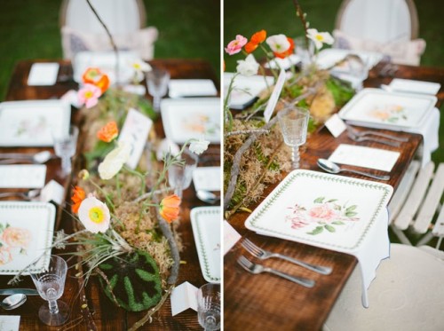 a spring wedding tablescape with a moss and bold bloom runner, floral plates, neutral linens and silver cutlery