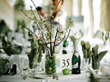 a green and white wedding tablescape with blooming branches, green apples, candles and green napkins and linens