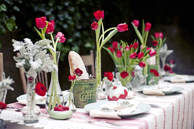 a bright spring wedding tablescape in fuchsia and green, with pale leaves, striped linens, bold blooms and bread in a tin can