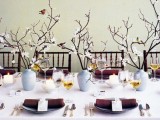 a fresh spring wedding tablescape with brown napkins, blooming branches, candles and cards feels like spring