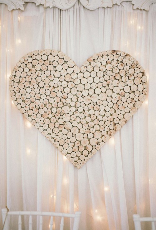 a large heart made of wooden slices is a cool and cozy rustic reception backdrop