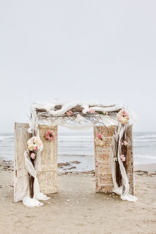 vintage doors, blooms, neutral fabric and branches make up a chic and refined wedding backdrop