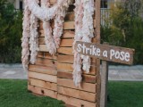 a pallet backdrop with wooden and fabric garlands on top that decorate it and make it more glam and fun