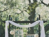 a unique wedding backdrop of dark stained wood, fabric, paper balls and vintage windows hanging