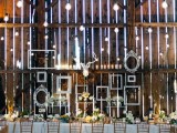 a pallet wall with white frames attached to it and lots of lights is a stylish idea for a vintage rustic wedding