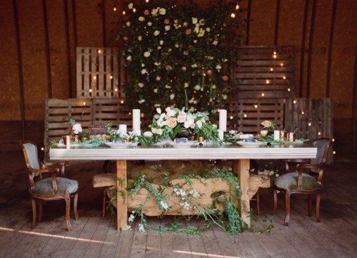 pallets with lights, greenery and blooms is a stylish wedding reception idea that will inspire