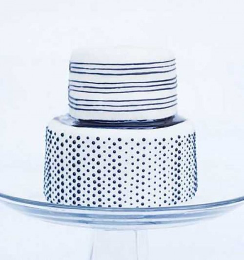 a white wedding cake decorated with black stripes and polka dots is a cool and fresh option