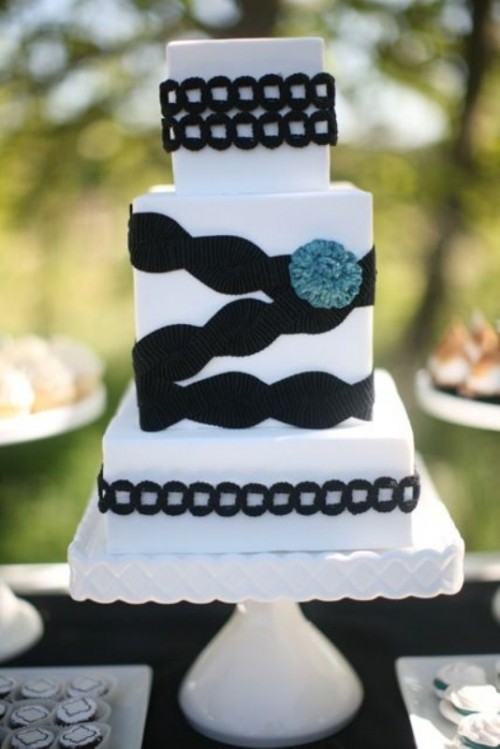 a white wedding cake decorated with black ribbons and lace plus a blue fluff is a unique option