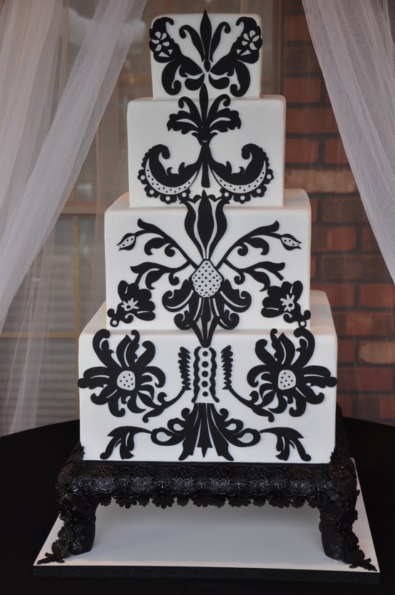 A white wedding cake decorated with unusual black patterns will fit a folksy wedding