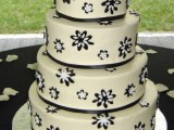 a white wedding cake decorated with black and white blooms and black ribbons