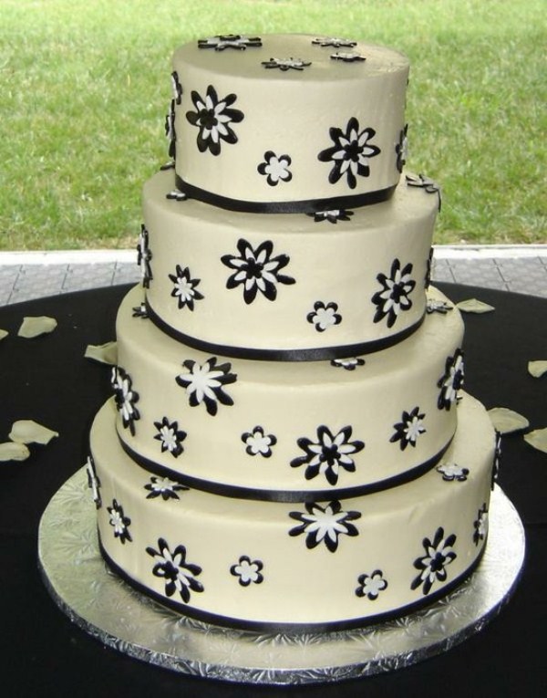 A white wedding cake decorated with black and white blooms and black ribbons