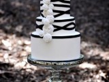 a white wedding cake decorated with black ribbons and white fluffies for a cool and bold look