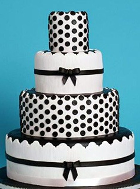 A white wedding cake decorated with black polka dots, ribbons and patterns for a playful and fun look