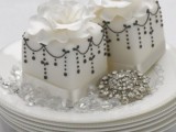 white square wedding mini cakes with black patterns and white sugar blooms on top