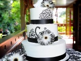 a black and white wedding cake decorated with ribbons, black patterns and sugar blooms plus a pretty topper