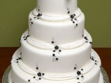 a white wedding cake decorated with small and subtle black flowers and a huge black ribbon bow on top