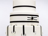 a white wedding cake decorated with black ribbons and bows, with a large sugar bow on top