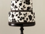 a white wedding cake decorated with black floral patterns and ribbons is a cool and bold idea to rock