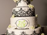 a black and white wedding cake decorated with lace and some sugar and fresh blooms and greenery
