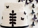 a black and white wedding cake with floral and butterfly appliques for a cute and whimsy wedding