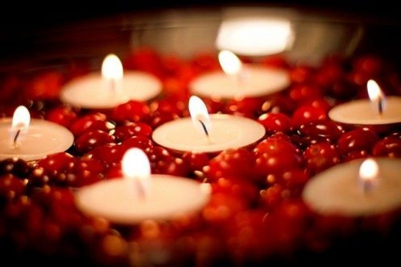 a wedding centerpiece of a bowl, some cranberries and floating candles to spruce up your fall or winter wedding decor